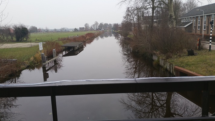 Wandelen over het Groot Frieslandpad op brug over Polderhoofdkanaal in Nij Beets