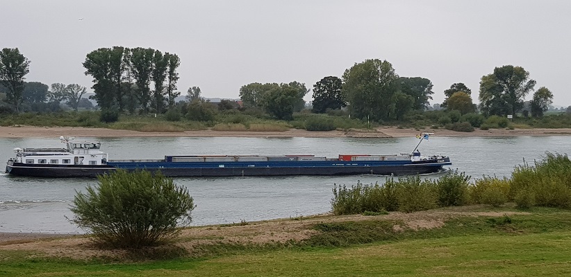 Wandelen over klompenpad Rijnweidepad bij scheepvaart op de Rijn bij Lobith