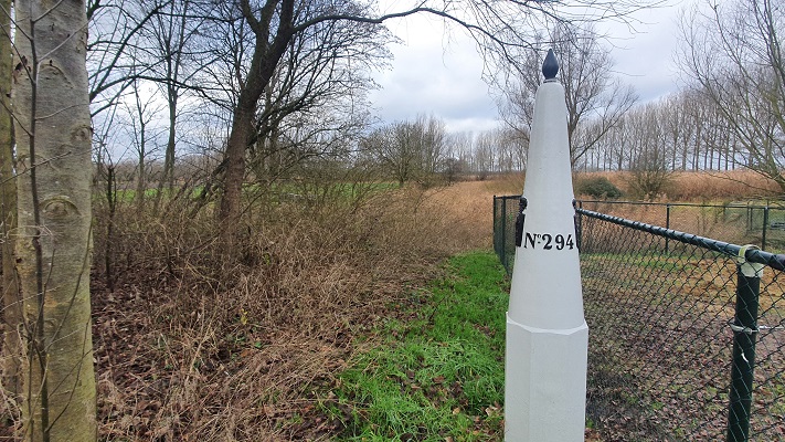 Wandeling over Grenslandpad van Kijkuit naar Oudeburgsesluis bij een grenspaal in Roode Sluis